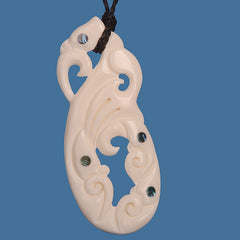 Carved bone pendant with intricate patterns on a blue background