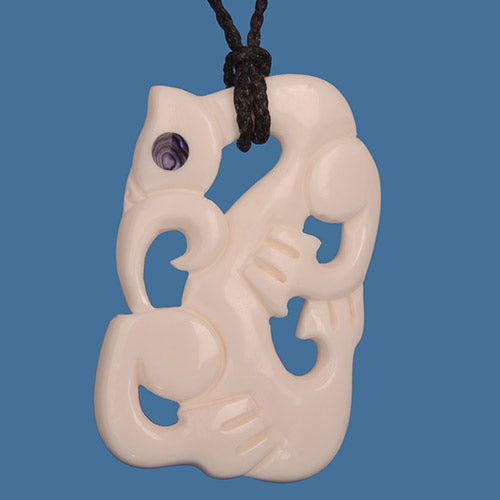 Carved bone pendant with intricate design on a blue background