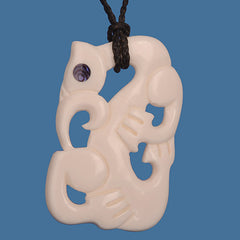 Carved bone pendant with intricate design on a blue background