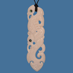 Carved bone pendant with intricate designs on a blue background