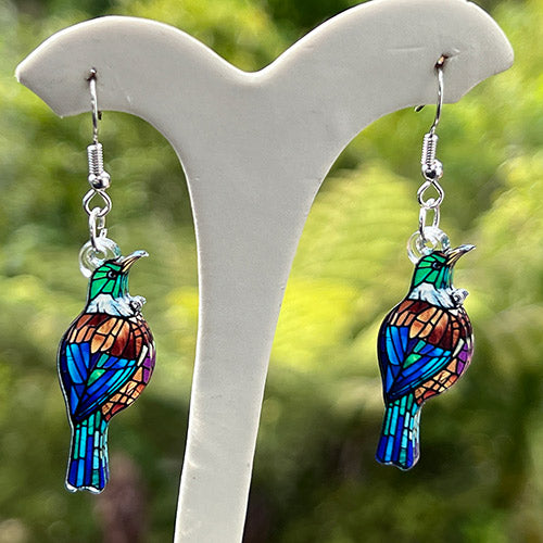 Colorful Tui earring with a blurred green and blue background