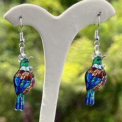 Colorful Tui earring with a blurred green and blue background