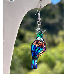 Colorful Tui earring with a blurred green and blue background