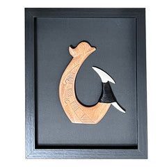 Wooden hook-shaped object in a black frame on a black background