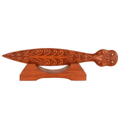 Wooden paddle with intricate carvings on a stand against a white background
