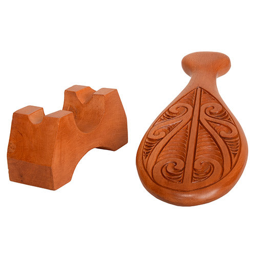 Wooden patu with intricate carvings on a white background