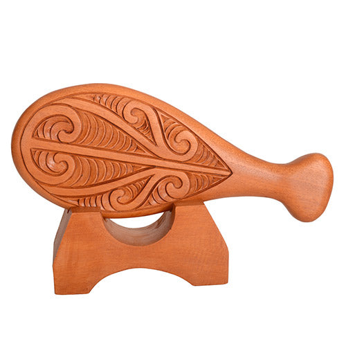 Wooden patu with intricate carvings on a white background