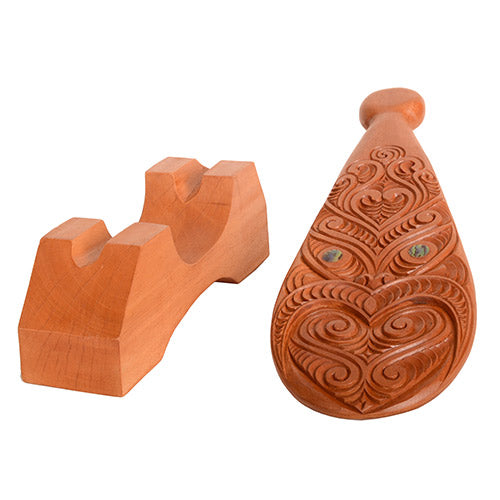 Wooden patu with intricate carvings on a white background