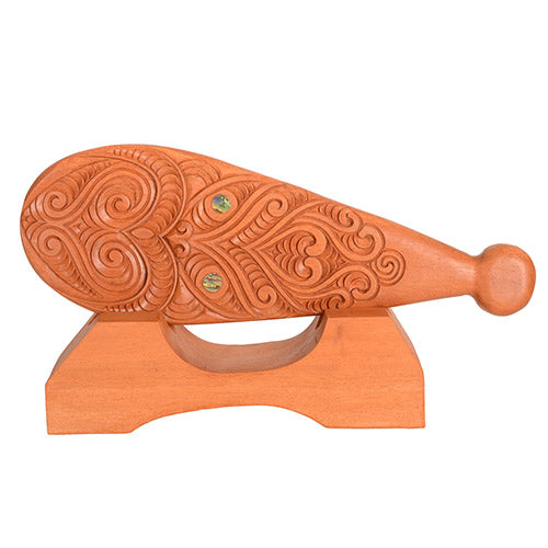 Wooden patu with intricate carvings on a white background