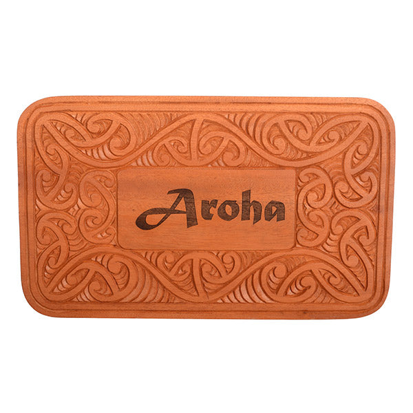 Wooden sign with intricate carvings and 'Aroha' engraving on a white background